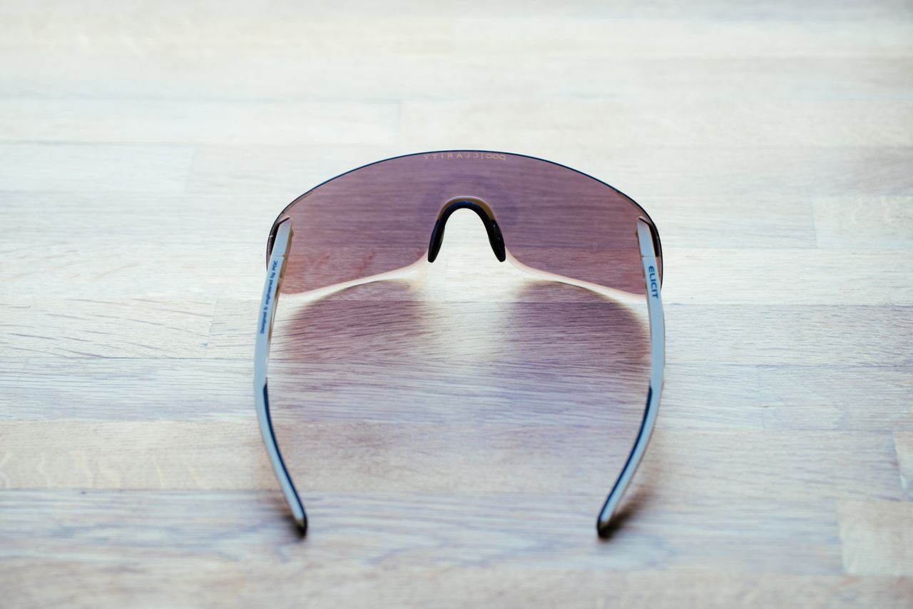 A set of frameless sunglasses with beige arms on a wooden surface