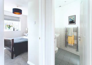 A bedroom and a bathroom with white walls and grey carpets