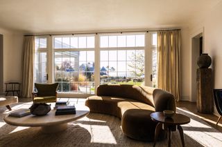 Brown curved sofa, green chair, round coffee table