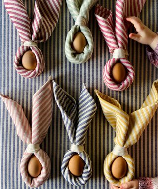 stripe napkins wrapped around eggs like bunny ears for an easter tablescape