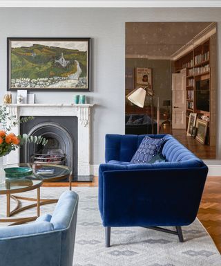 Living room with blue fluted sofa and mirror wall