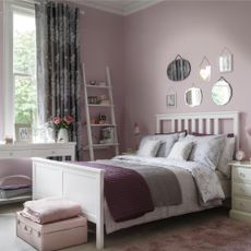 A cosy bedroom in purples and pinks with lavish curtains