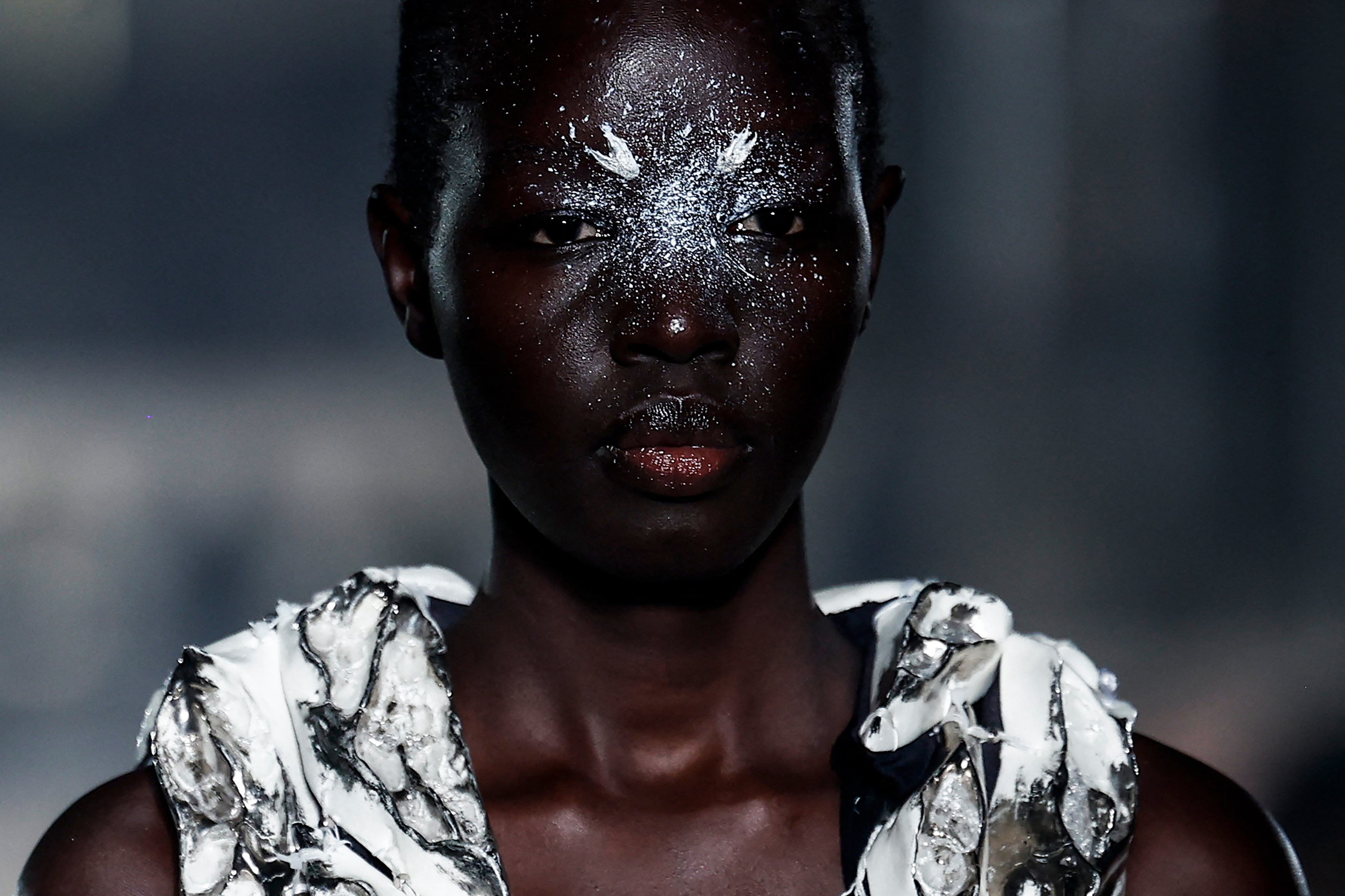a black model with glittery face makeup walks the runway during paris couture week