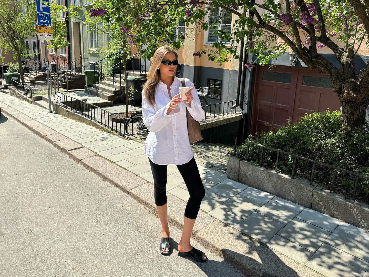 Fashion person Sofia Boman wears a legging outfit 2025. She wears a white shirt, black capri leggings and black mules.