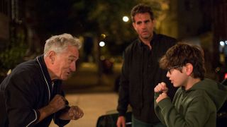 a grandpa (Robert De Niro) and his grandson (William Fitzgerald) hold up boxing stances as the dad (Bobby Cannavale) looks on, in the movie 'Ezra'