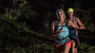 A man and woman fastpacking wearing head torches