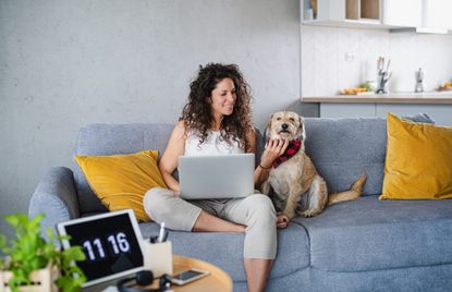 Woman looking for how to make money from home with dog on the sofa next to her