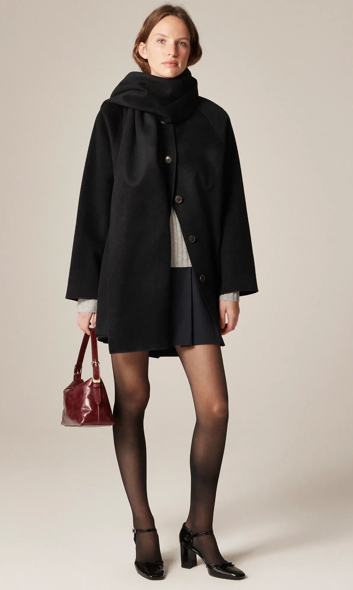 A model wearing a black thigh-length scarf coat in drapey wool blend.