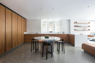 A contemporary white kitchen with poured concrete flooring and wooden handleless cabinetry.