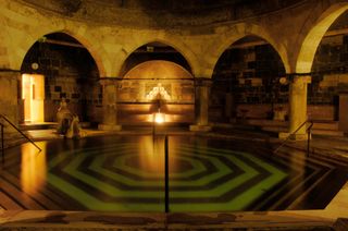 The Rudas bath in Budapest. A large in door bath with nested angular shapes on the bottom and arched door ways all around it.