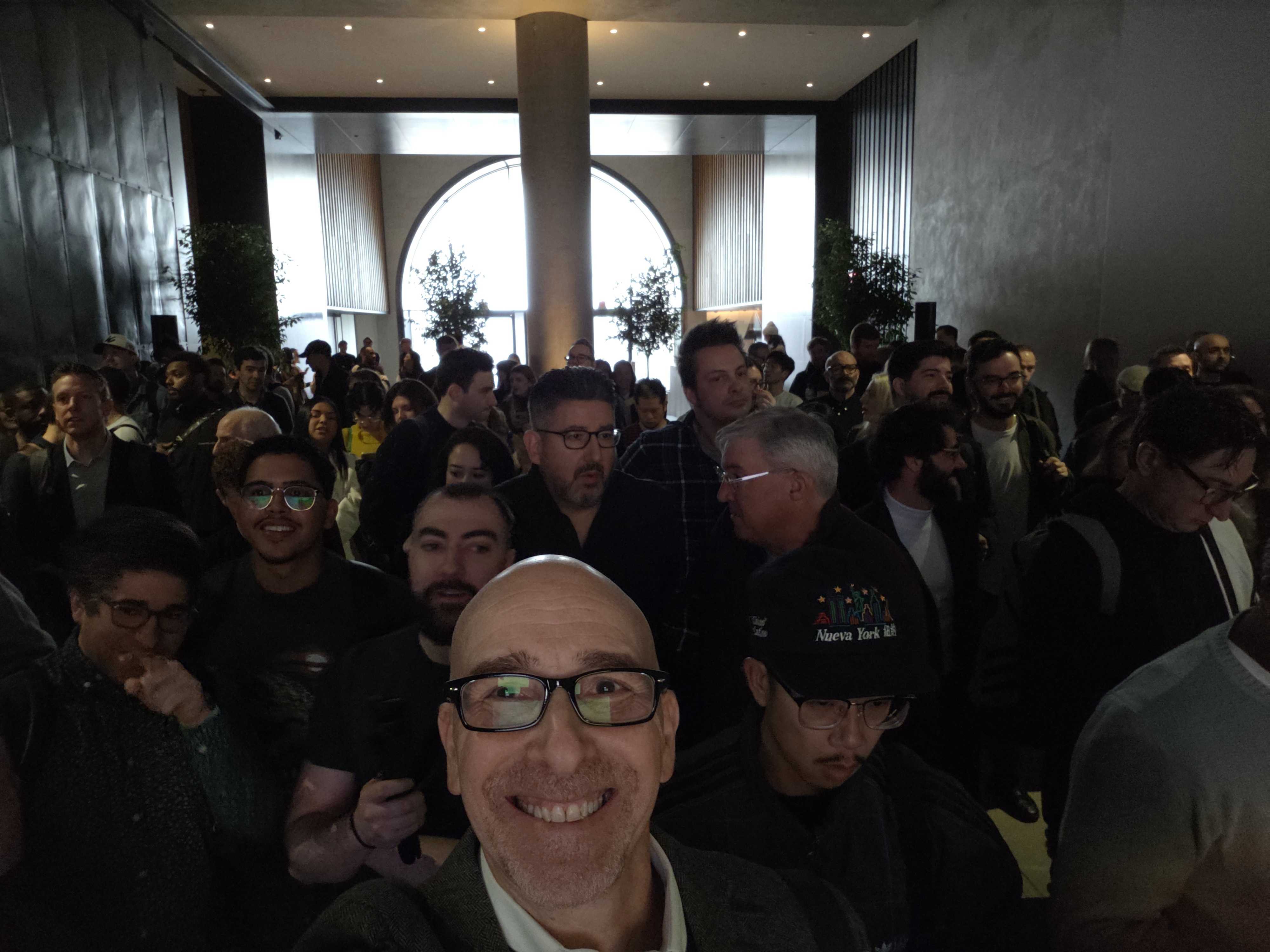 Lots of people standing inside an auditorium