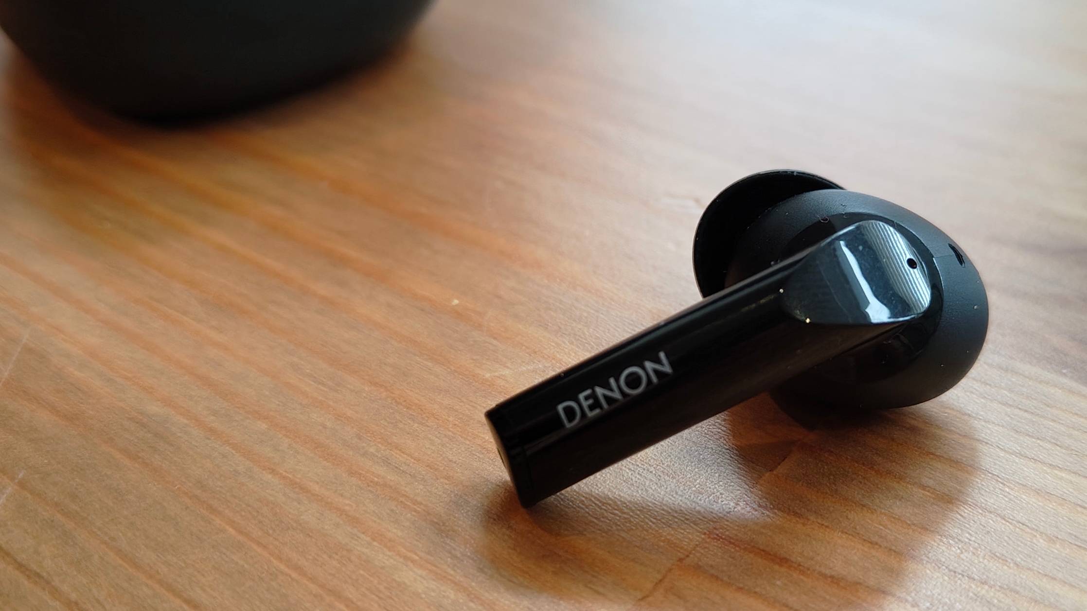 The Denon AH-C840NCW against a wooden table.
