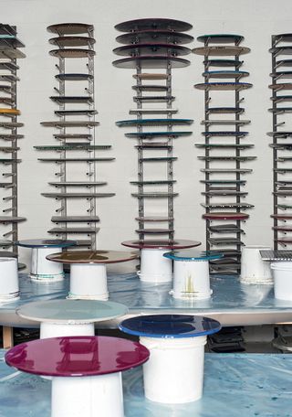 Multiple circular resin tabletops in a workshop with irregular designed wall shelves
