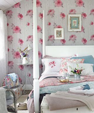 Bedroom with pink rose wallpaper and white four poster bed