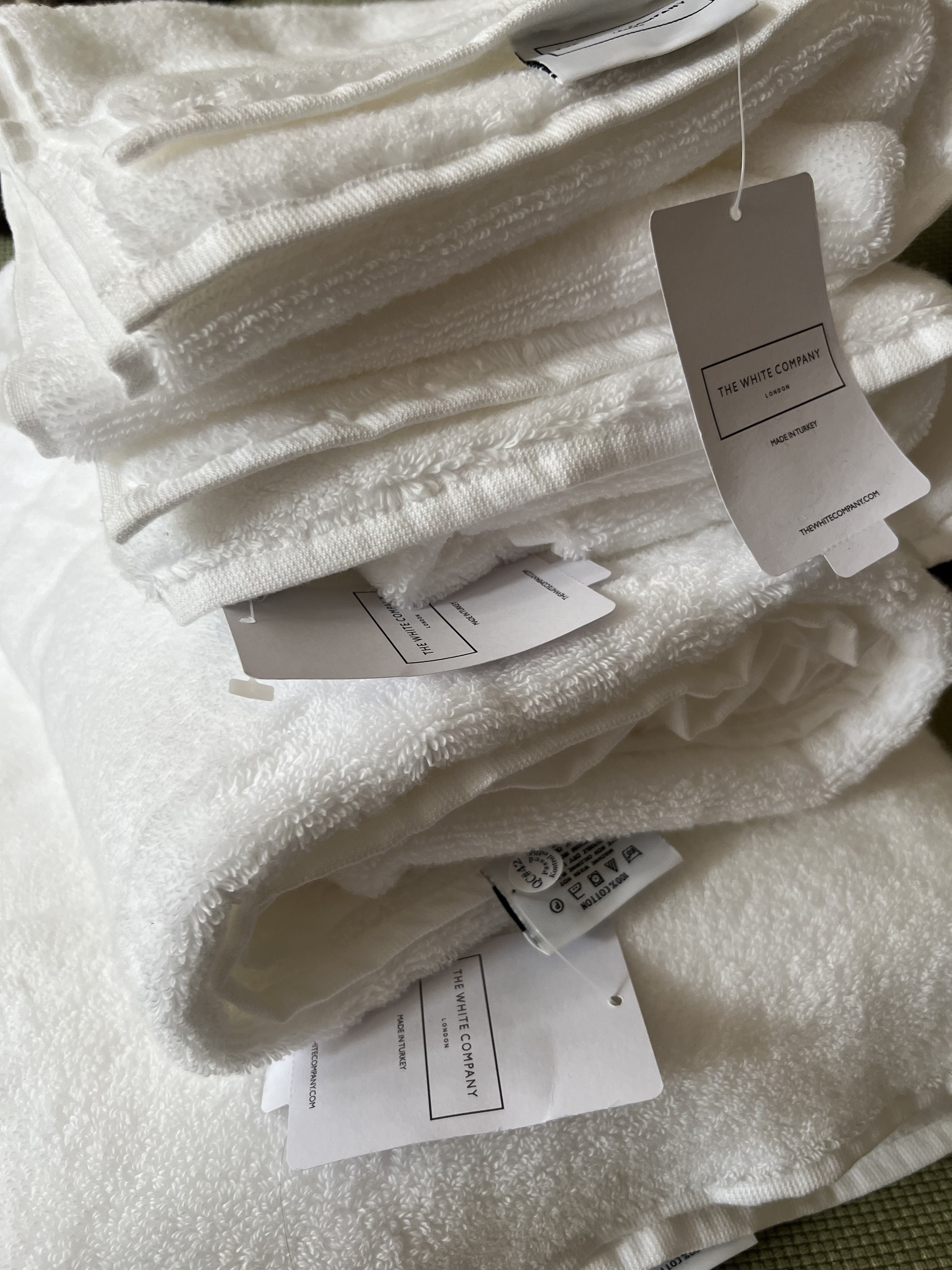 Close-up of a stack of white towels from The White Company with the tags in view