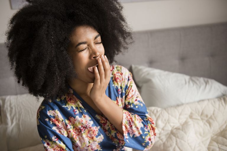 African American woman sitting in bed and yawning