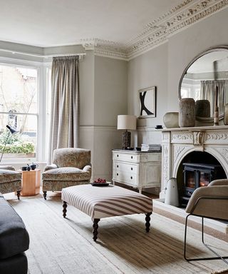 A classical living room in neutral color scheme with architectural features and pale paisley armchairs.