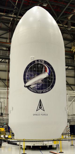 an egg-shaped rocket payload fairing in a hangar with the words "United States Space Force"