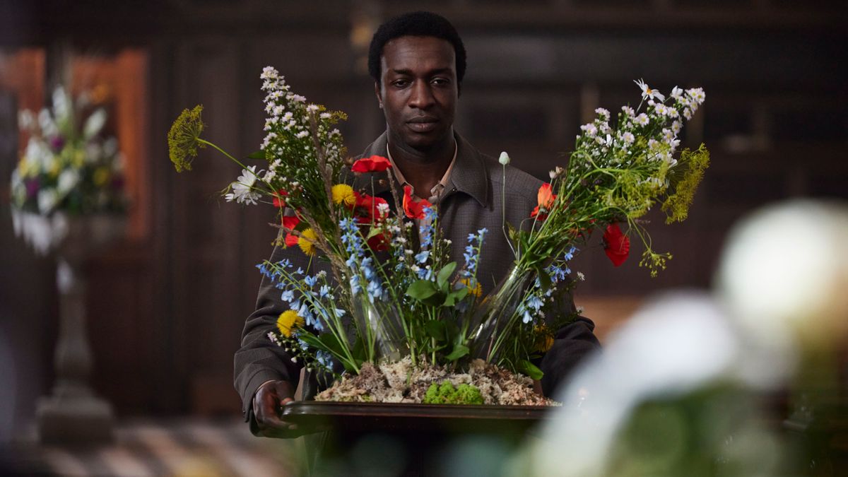 Cyril carrying a flower display in a church looking serious in Call the Midwife season 14 ep 2