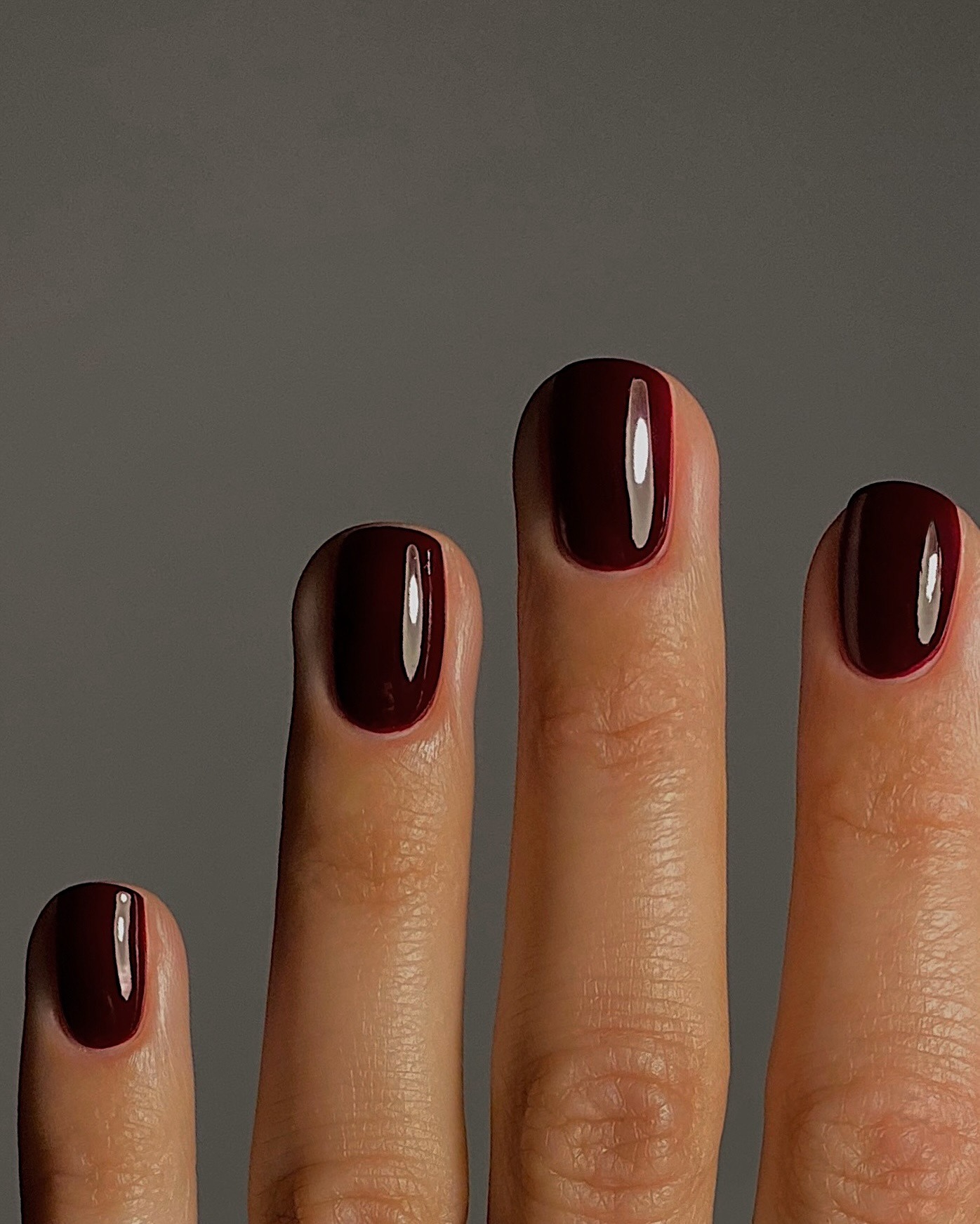 A close-up of hands painted with dark red nail polish