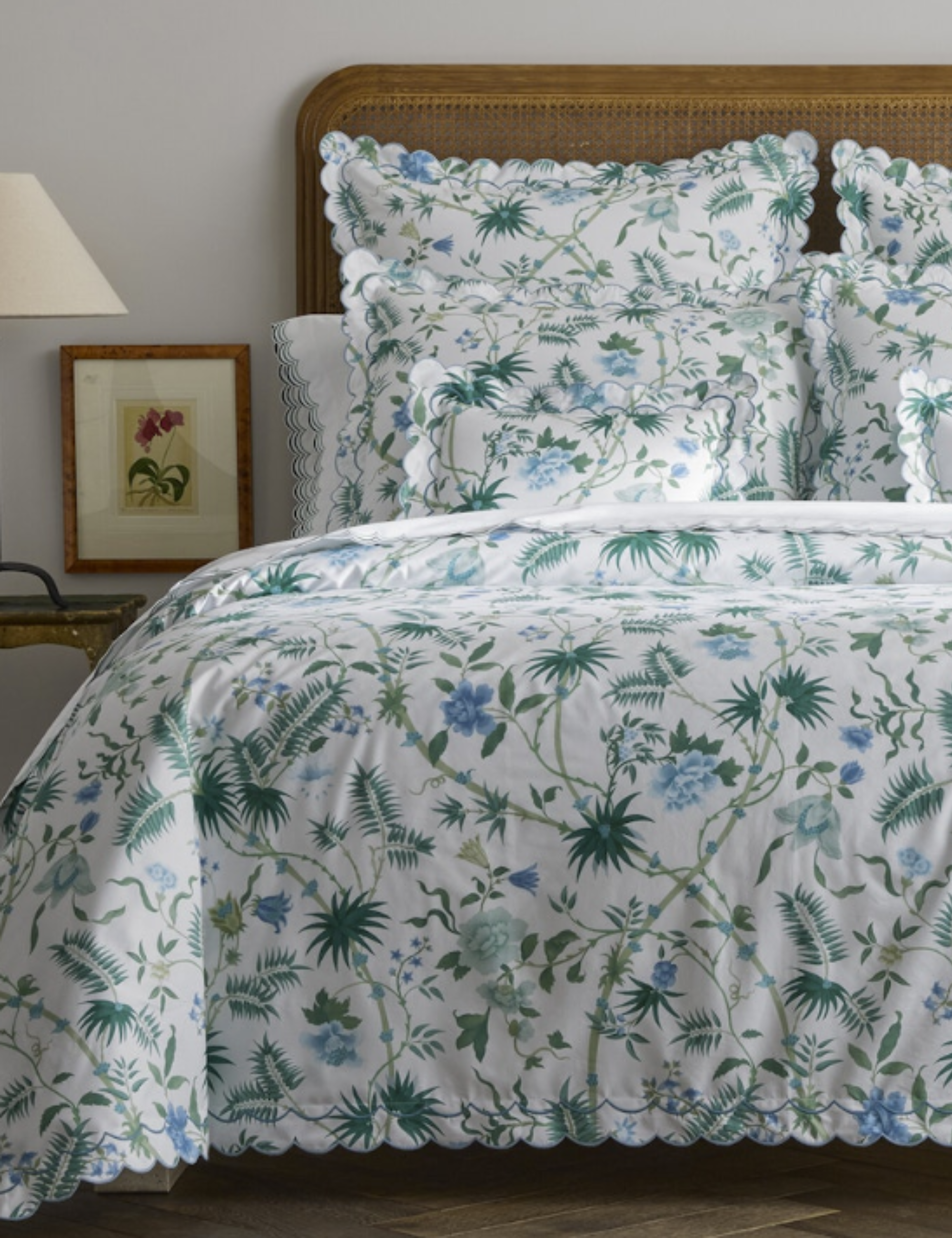 Palm leaf motif bedding styled atop of a bed featuring a rattan headboard