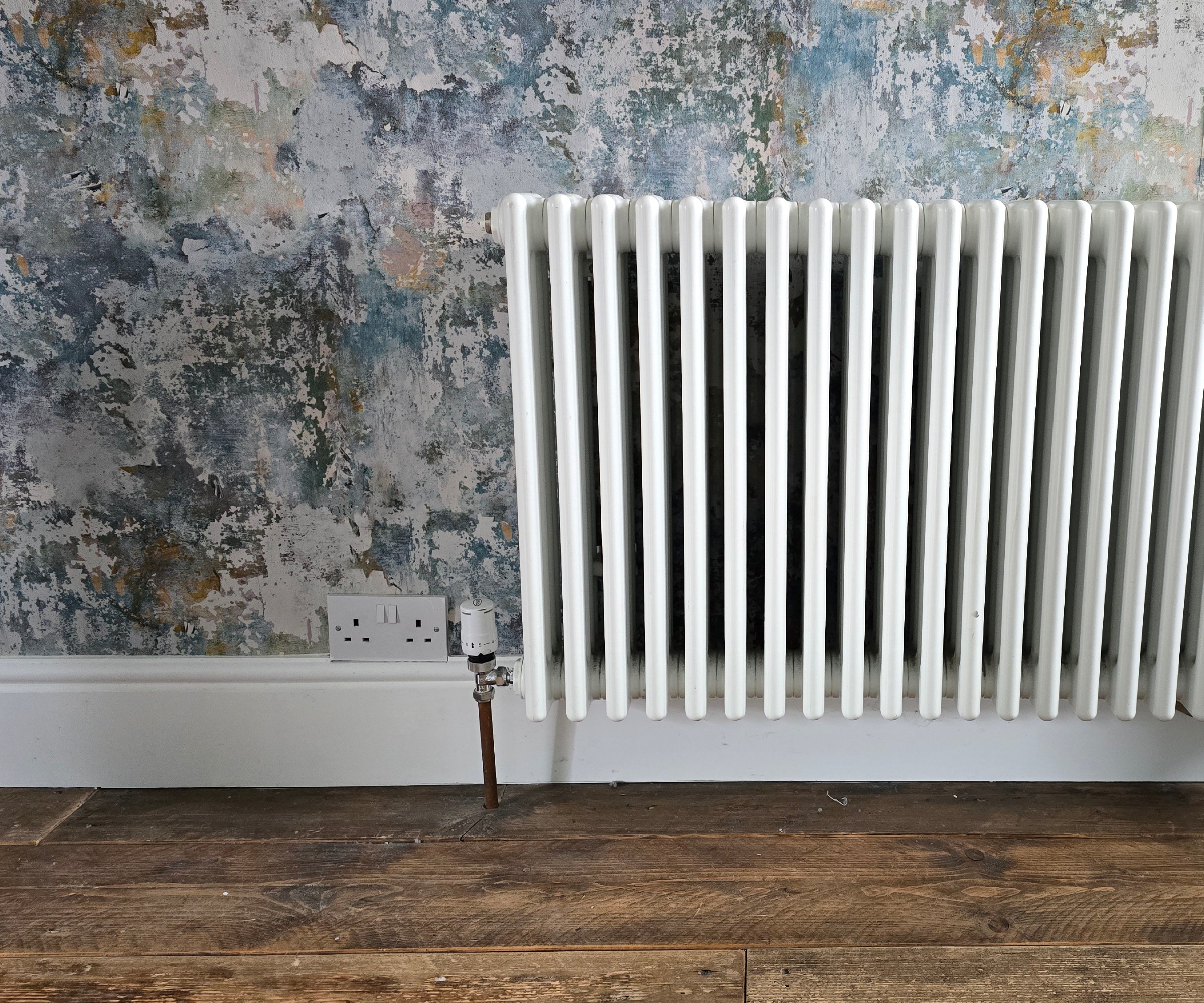 Hallway with blue and teal toned wallpaper and old fashioned radiator