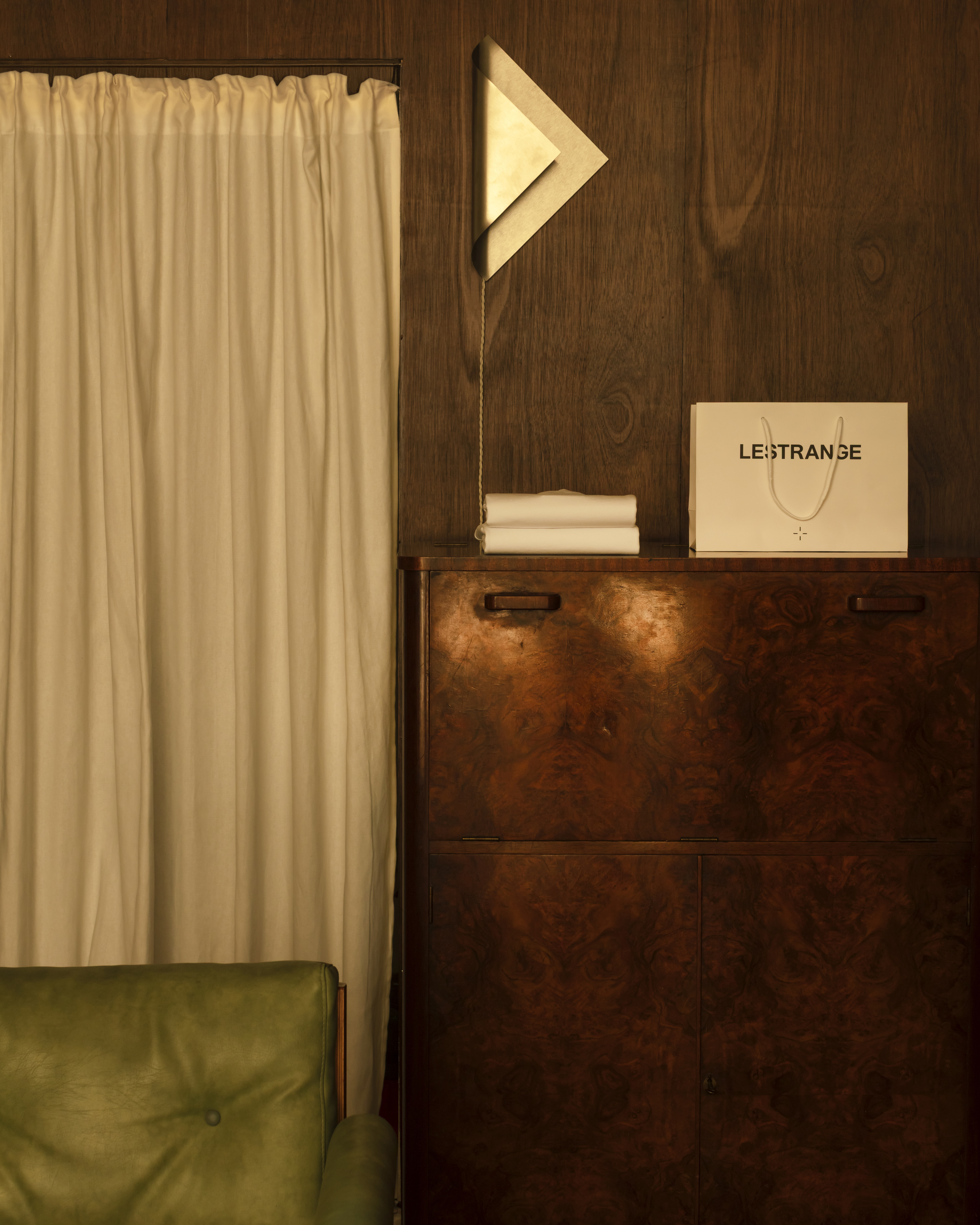 Different corners of a sleek menswear store clad in warm woods, beige drapery, and silver and mint green accents.