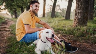 Man and dog sitting together in forest