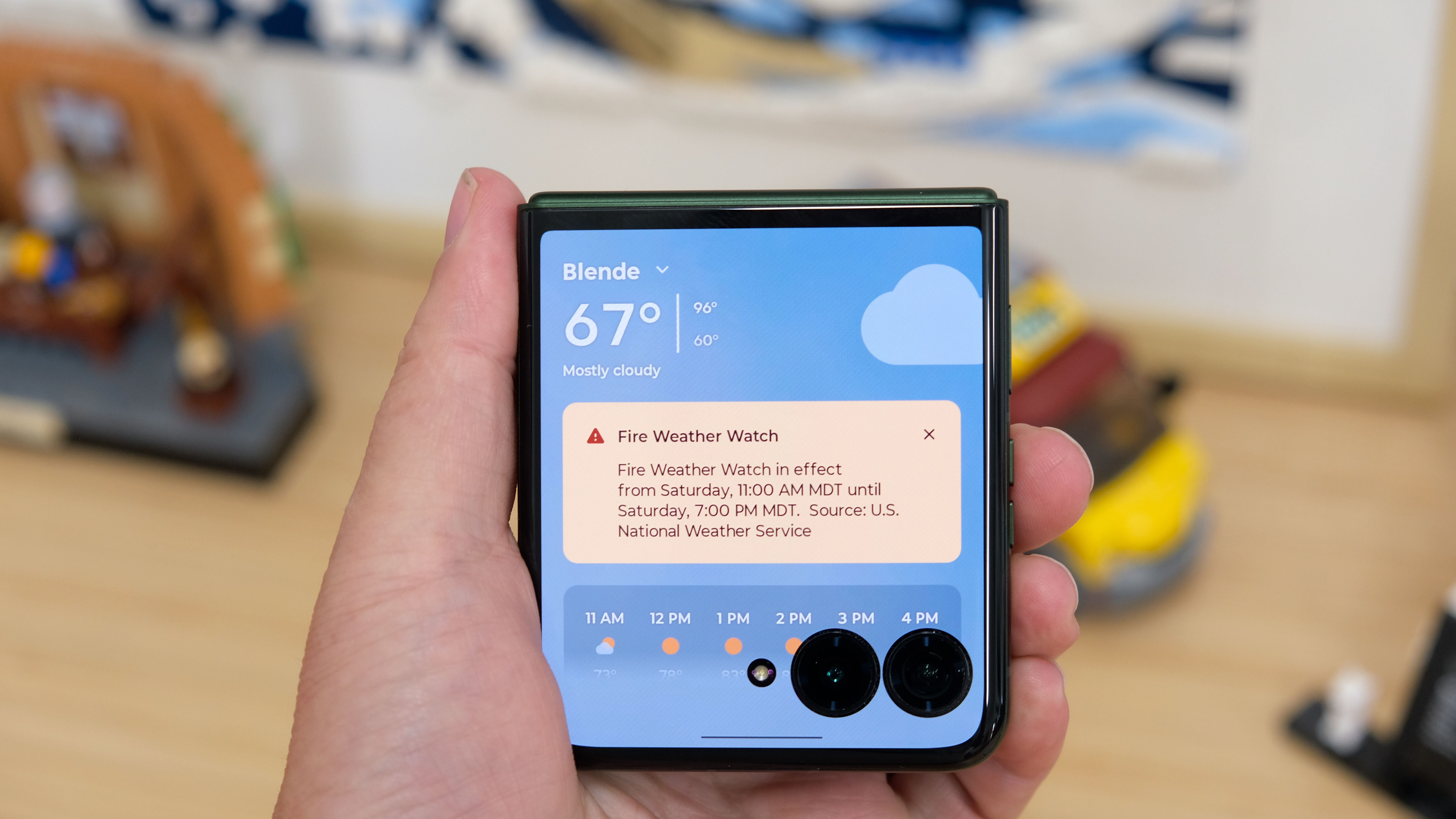 The Motorola Razr Plus 2026 in the hand and on a wooden table