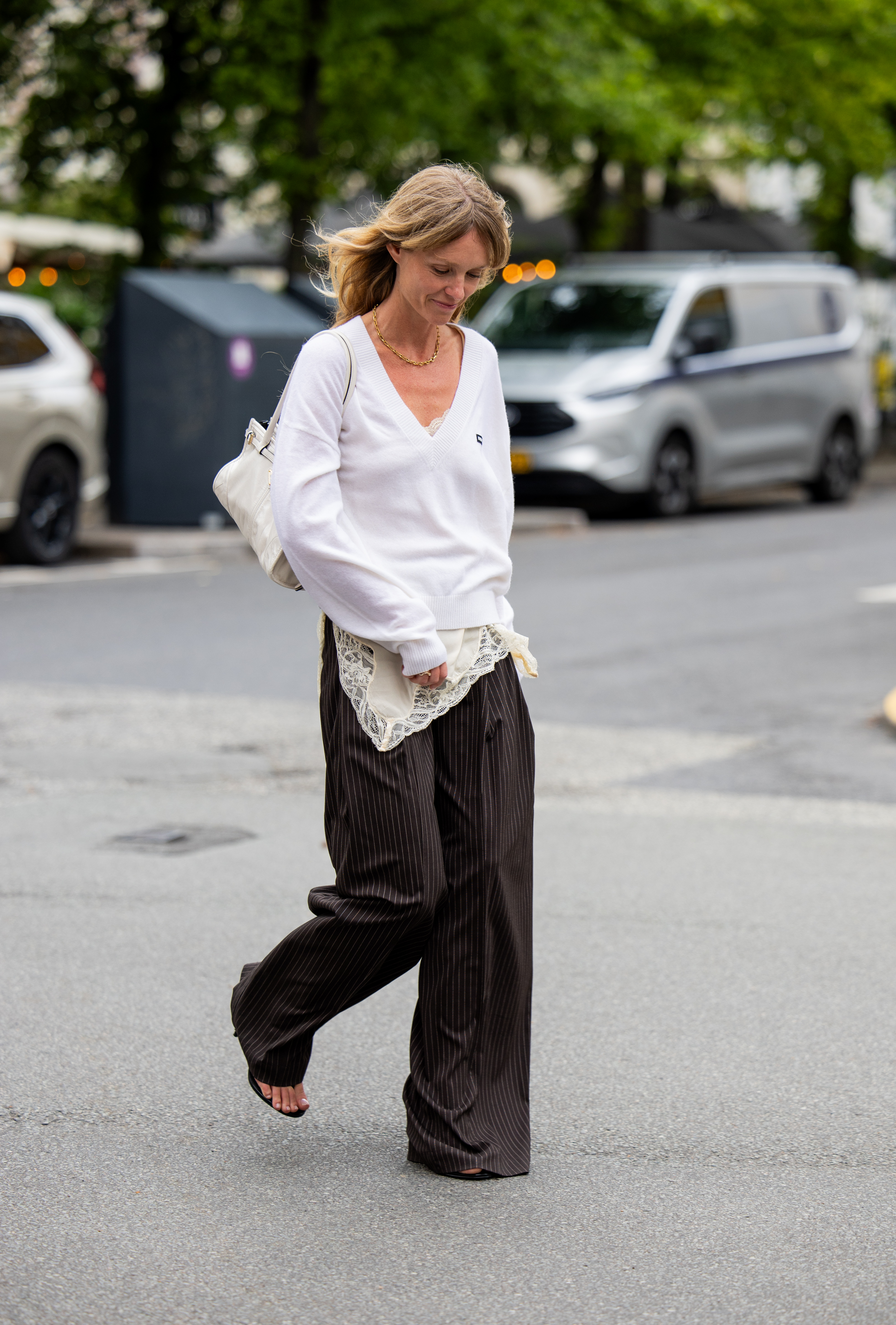 COPENHAGEN, DENMARK - AUGUST 04: Jeanette Friis Madsen wears white v neck jumper, laced beige dress, black white striped pants, bag outside Freya Dalsj&amp;oslash; during Copenhagen Fashion Week day one on August 04, 2025 in Copenhagen, Denmark. (Photo by Christian Vierig/Getty Images)