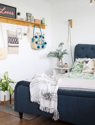 A white bedroom with navy blue bed and open shelving