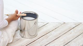 woman holding a paint brush on a white wooden deck