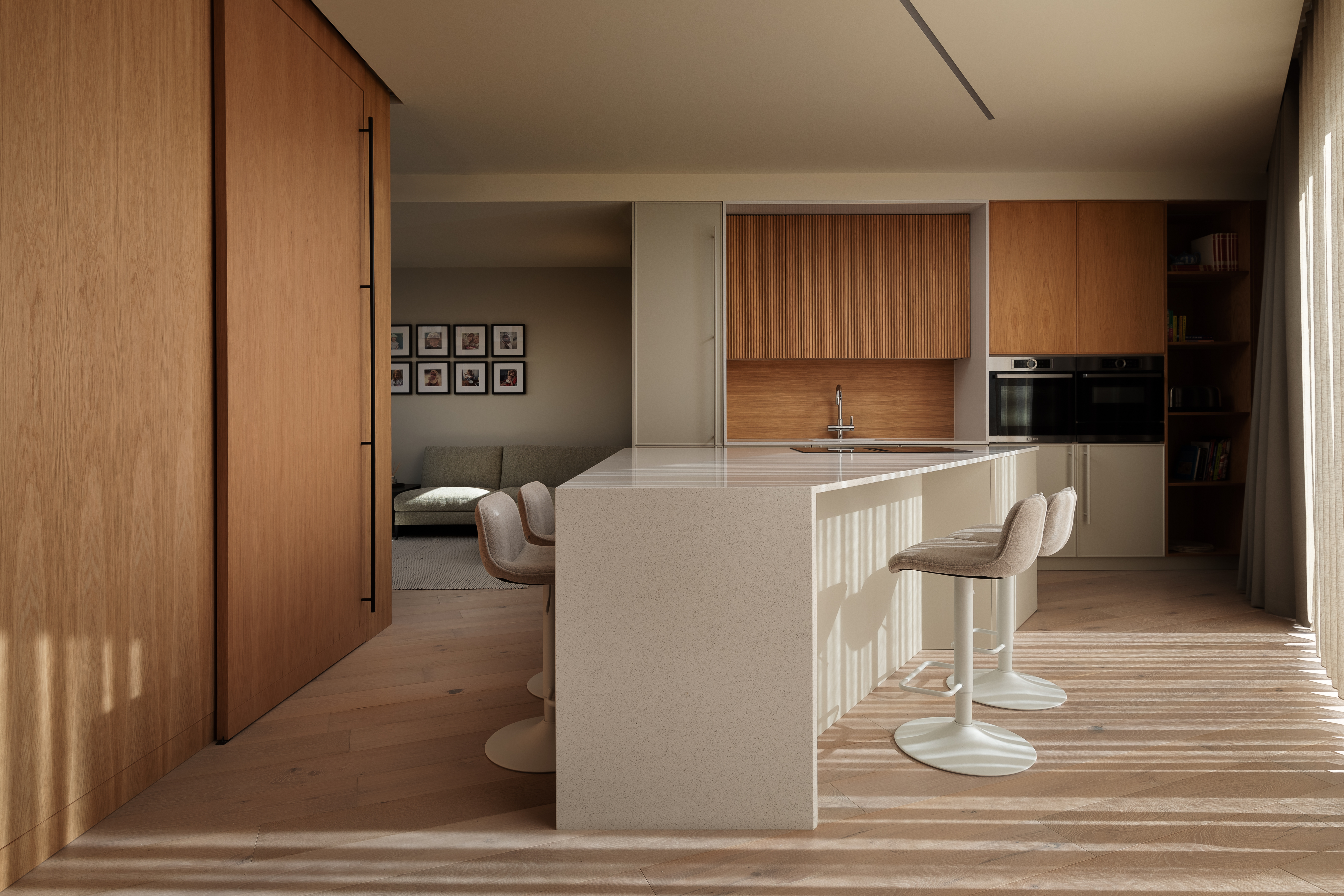 A kitchen island designed in a triangular shape with bar stools and seating next to it
