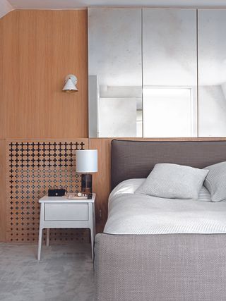 A neutral, minimalist bedroom with a wood panelled wall