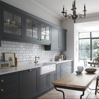 Pictures of kitchens, showing gray cabinetry, white subway tiled backsplash and a chandelier in a white scheme.