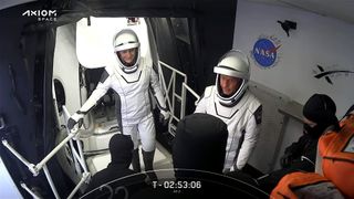 Ax-2 astronauts in spacesuits in Crew Access Arm white room preparing to enter Dragon.