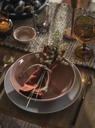 fall table with russet and gray tableware, napkin with foliage sprig, amber glassware, coir runner