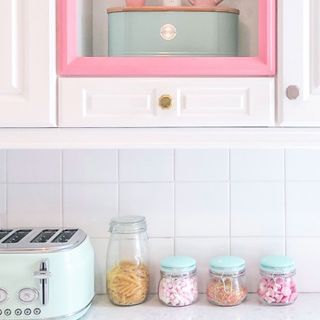 Pink tile kitchen space with pink accents and storage jars with pastel lids