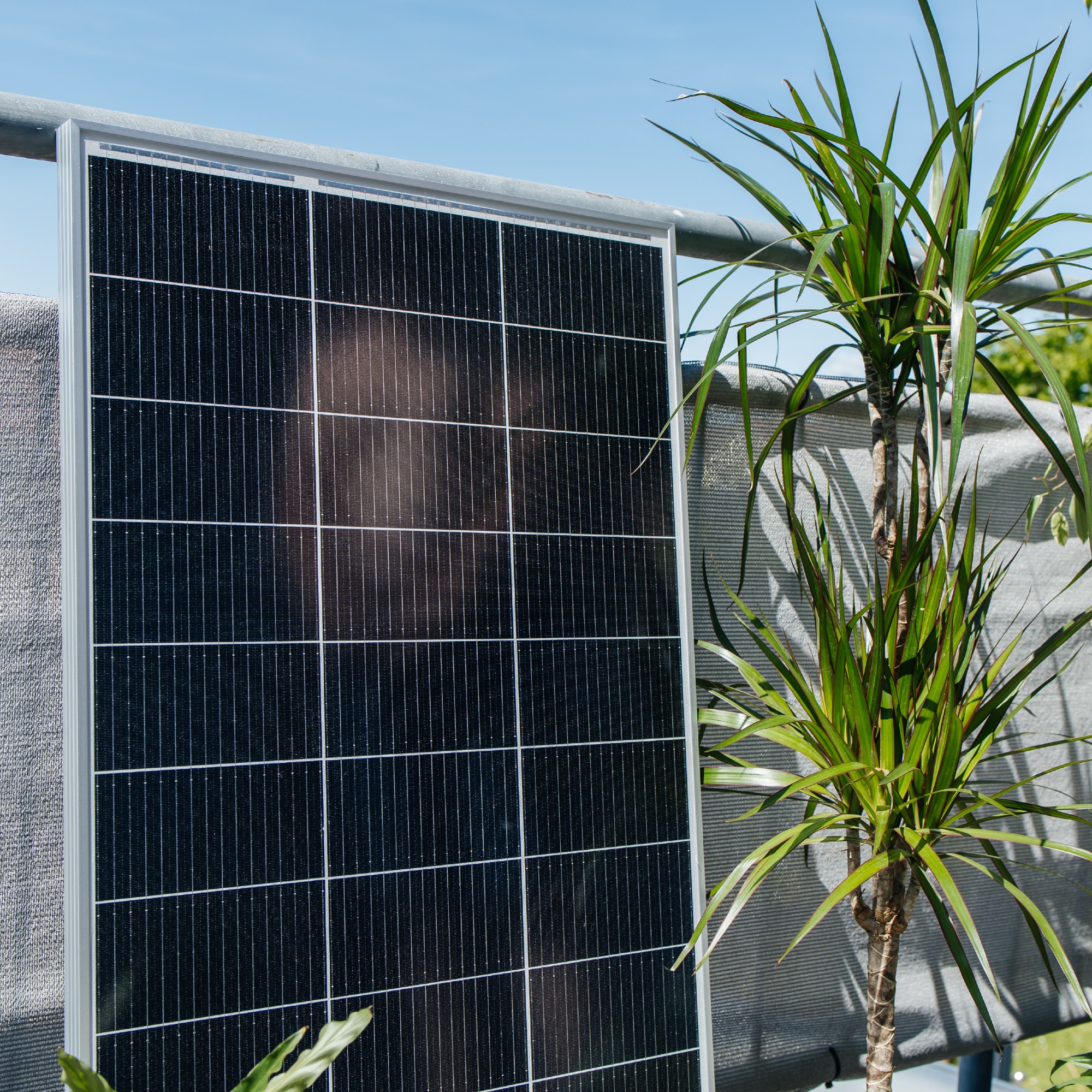 Solar panel installed on a sunny balcony, next to potted plants