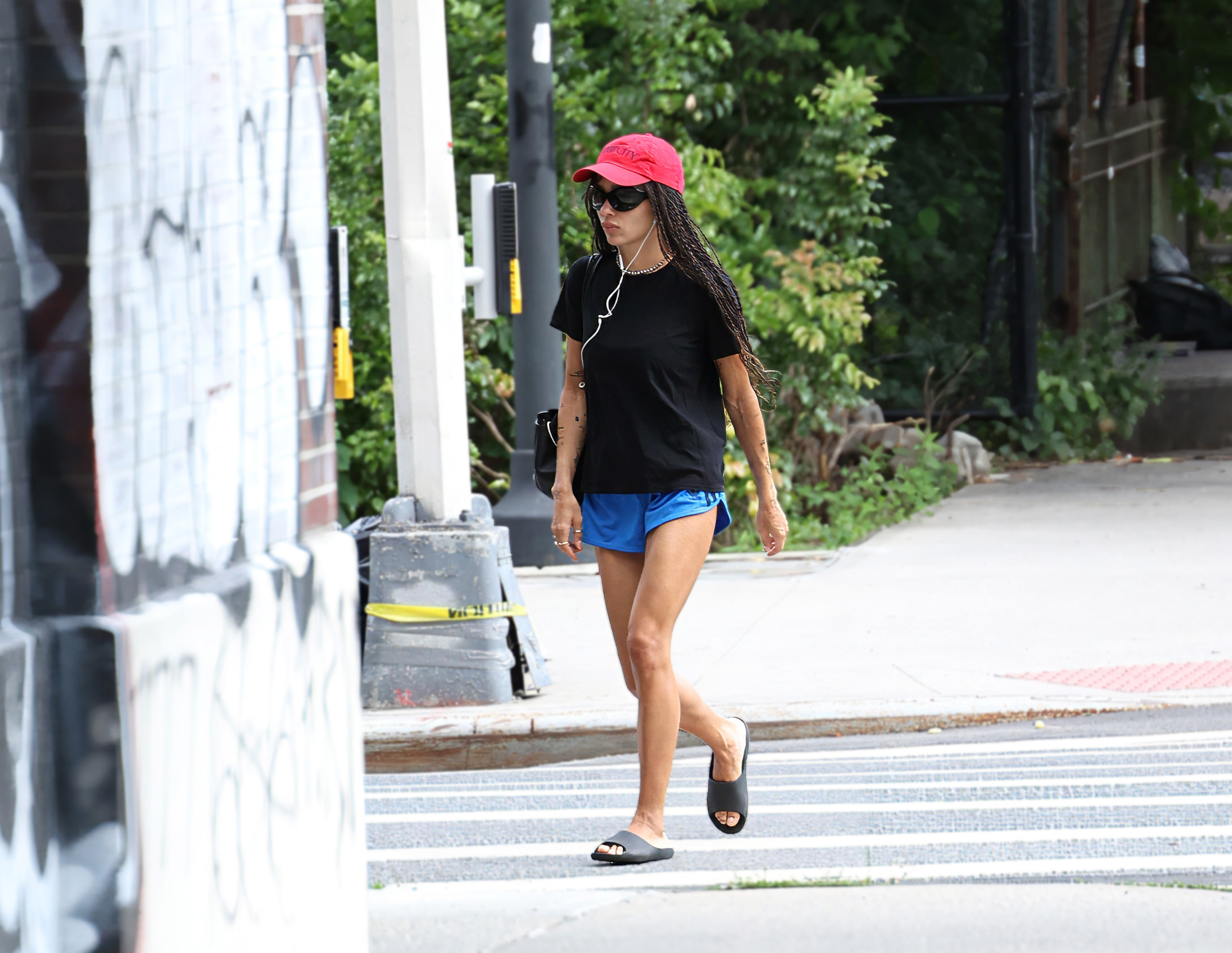 Zo&amp;euml; Kravitz wears a red Sex and the City baseball cap, blue Adidas shorts, and rubber slides on August 28, 2026 in New York City