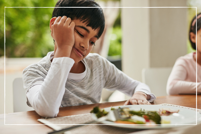 Smiling child with a plate of food in front of him