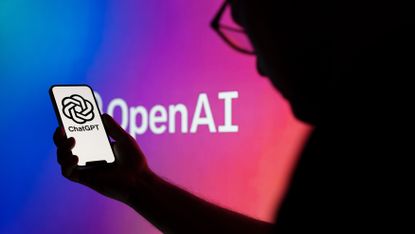 Someone holding a smartphone with the ChatGPT logo in front of a multicoloured background with the OpenAI branding