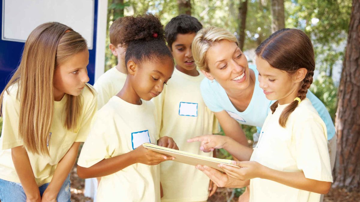 Female teacher and young students outdoors in the summer