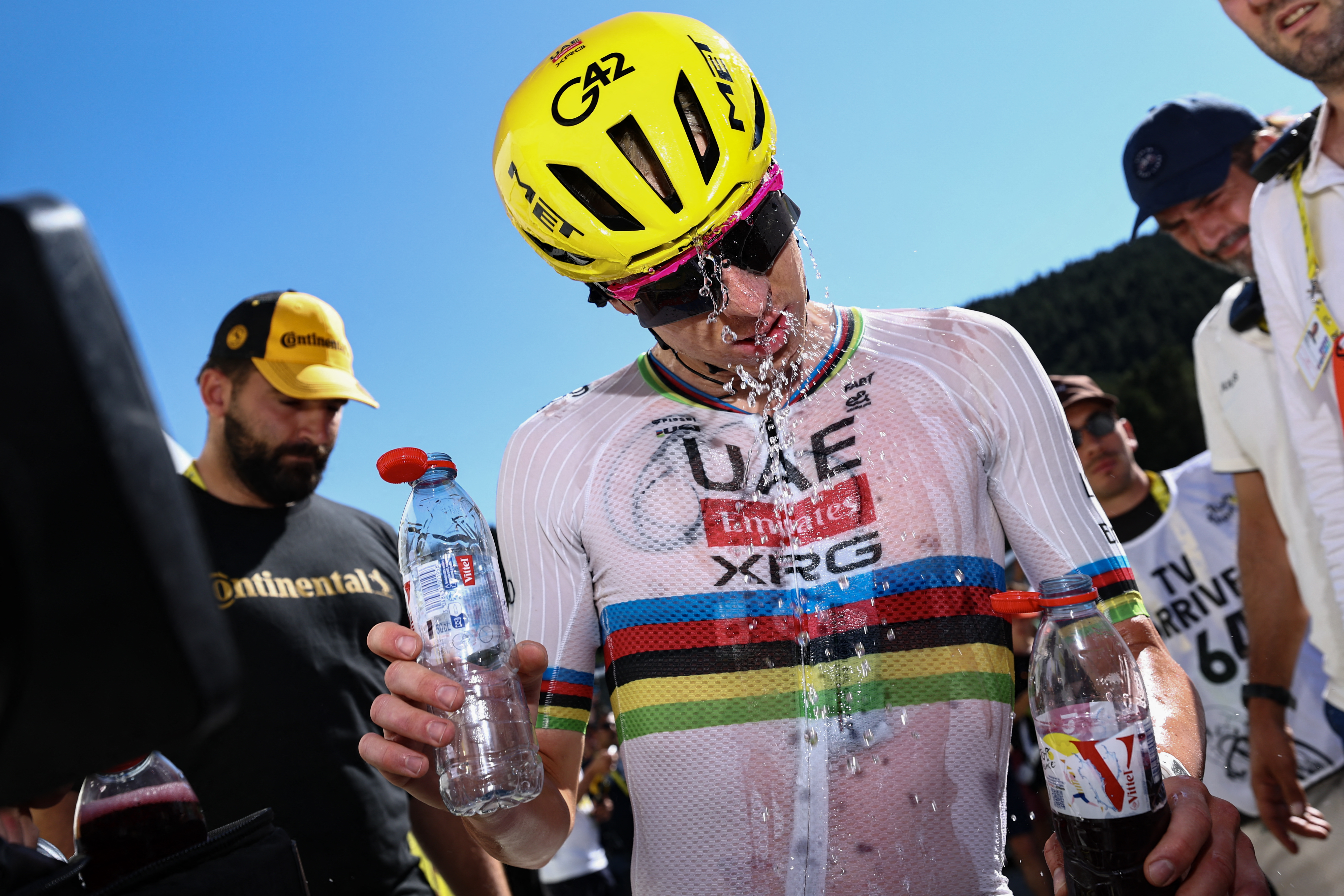 Tadej Pogačar cools down at the Tour de France by pouring a bottle of water over his helmet after stage 3 in Les Angles