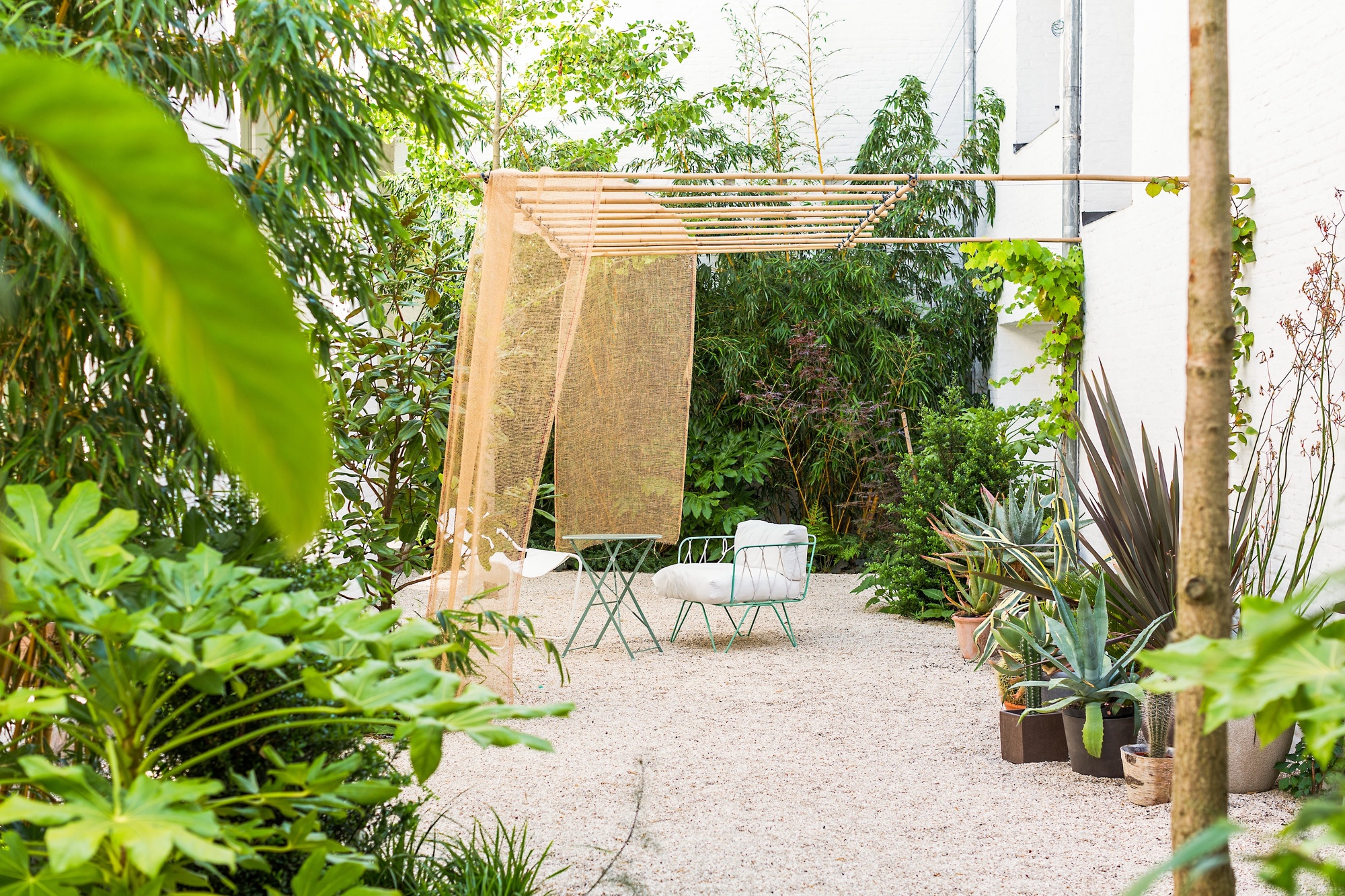 outdoor garden with pergola, pebbled garden, lush foliage, and a table and chair