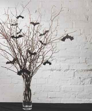 DIY Halloween decoration with sticks and bat decorations in glass vase
