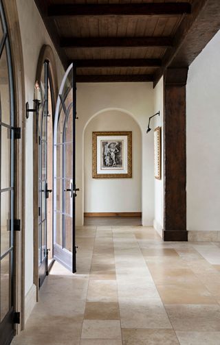 galleried hallway with pale stone floors and steel doors