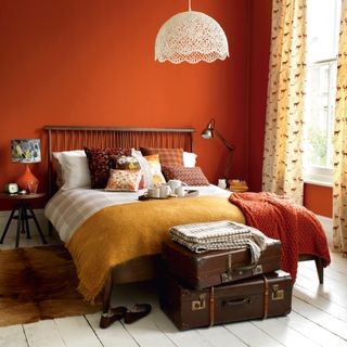 orange bedroom with layered cushions and patterned curtains