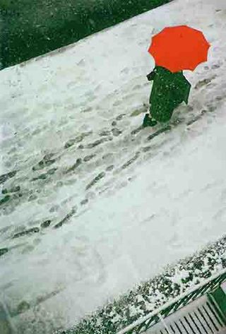 a top down view of a person walking in the snow holding a red umbrella, there are footprints in the snow