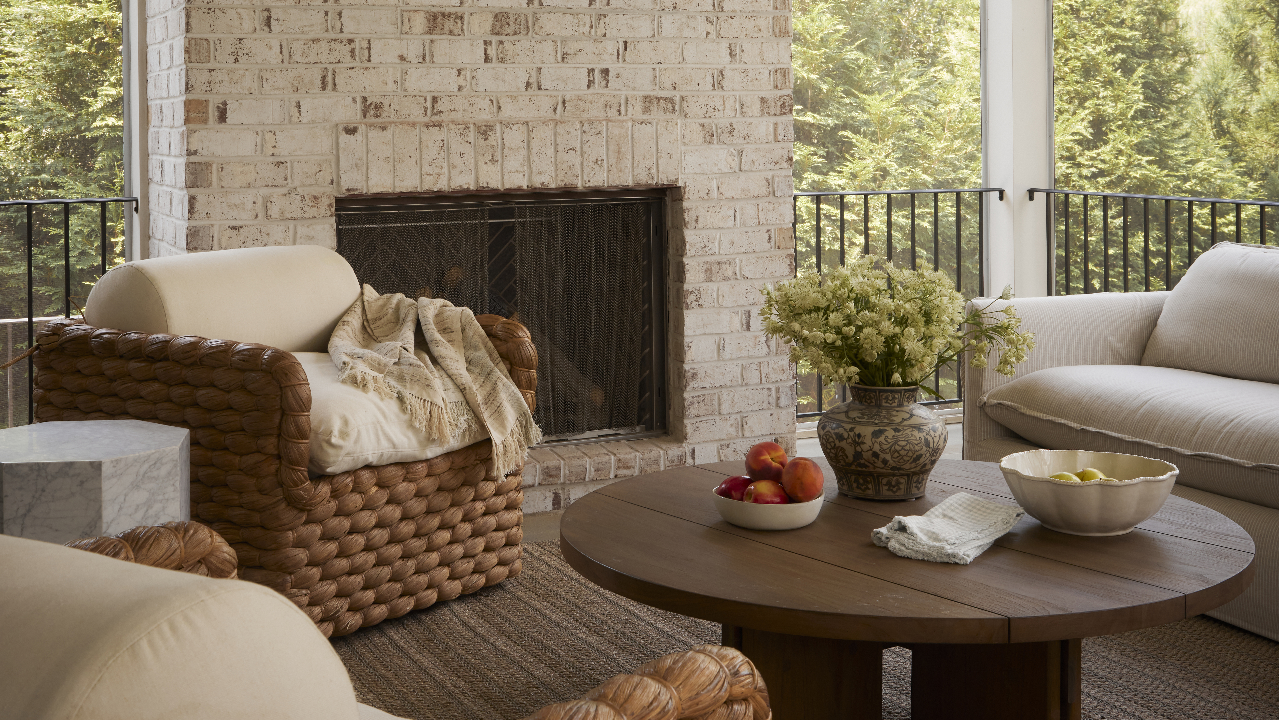 living room with floral arrangement on a round coffee table and wicker furniture